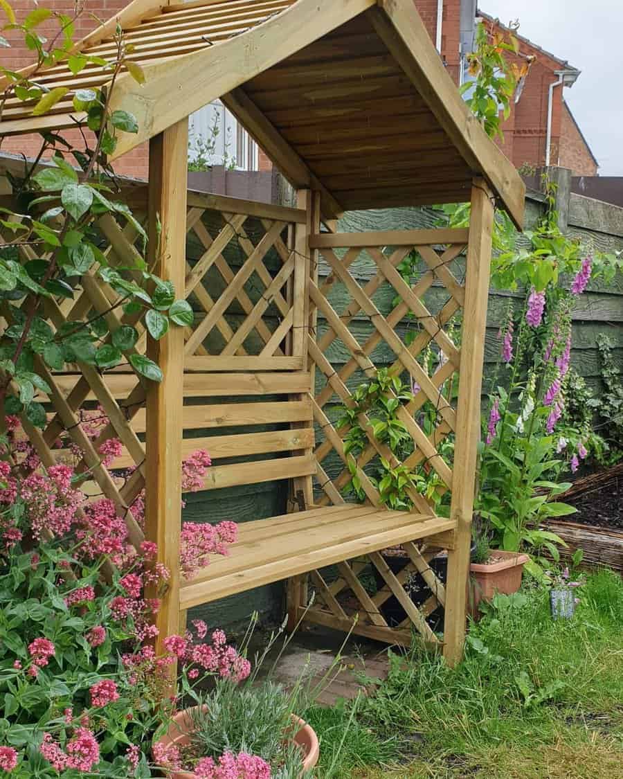 Wooden garden arbor with bench surrounded by flowers