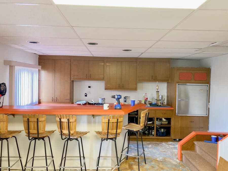 Simple basement bar with wooden stools and orange countertop