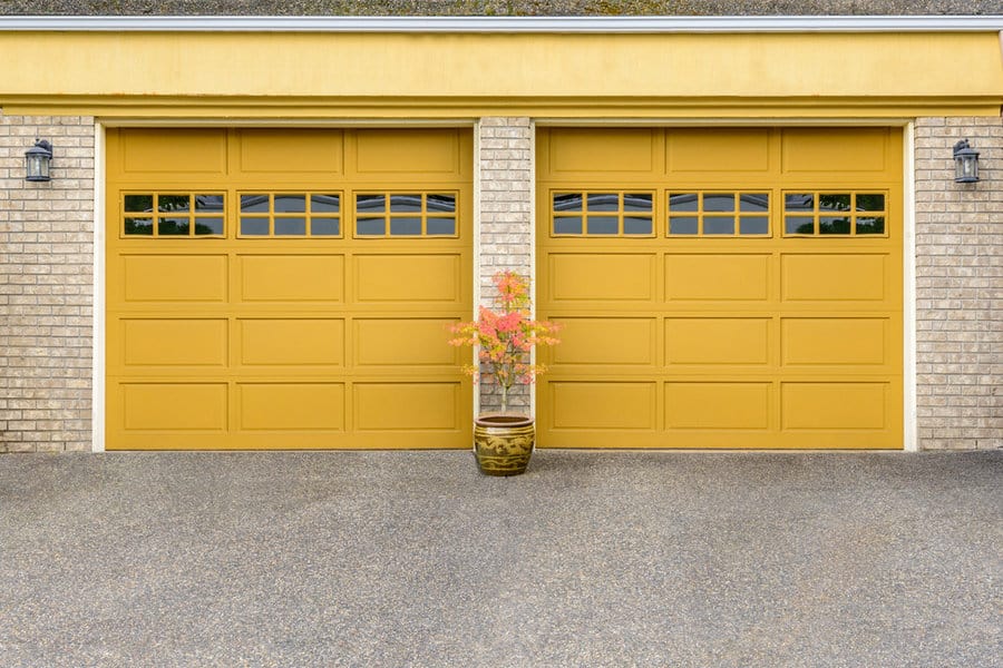 Painted Garage Door Ideas 3 Brick house with double yellow garage doors and a potted plant