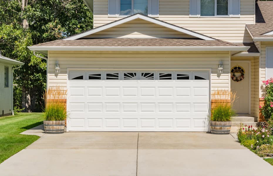 White Garage Door Ideas 1 Suburban home with a white paneled garage door and greenery